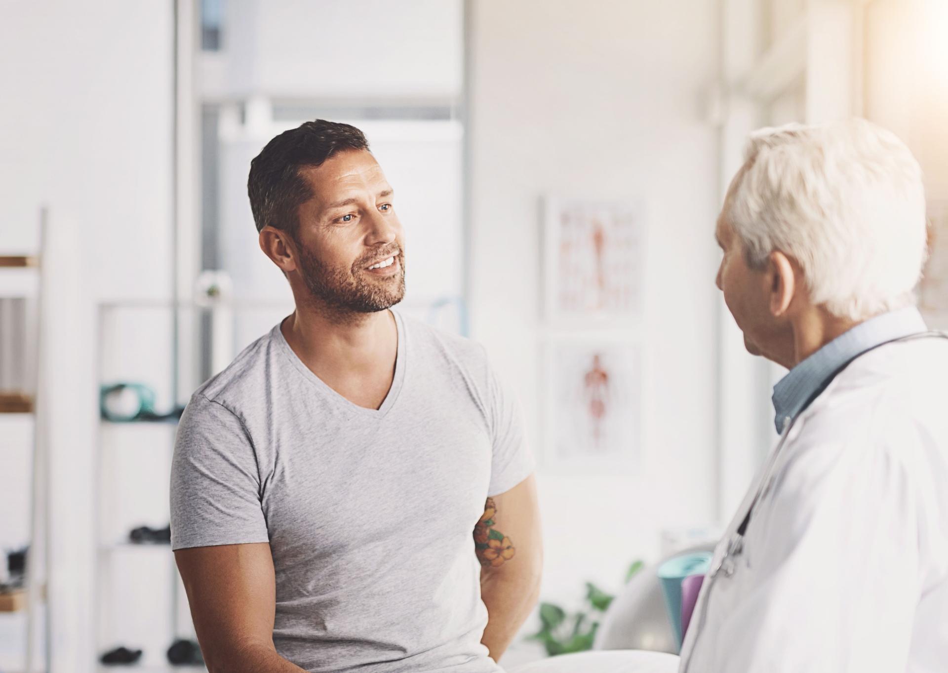 Doctor, office and man with discussion in consultation for medical treatment, planning and feedback. Healthcare, people and mature professional with advice for physiatry, checkup and information